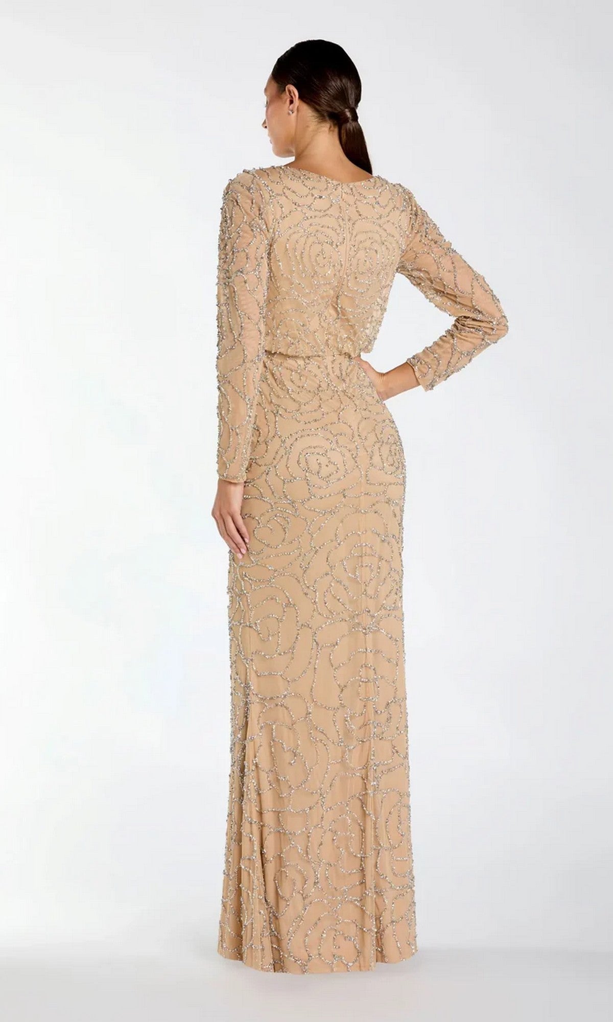 A woman stands with her back to the camera against a plain background, wearing the Long Formal Dress: Mac Duggal 6189—a sophisticated, floor-length beige gown featuring long sleeves and silver beaded swirl patterns, perfectly embodying Mac Duggal’s elegant, formal style.